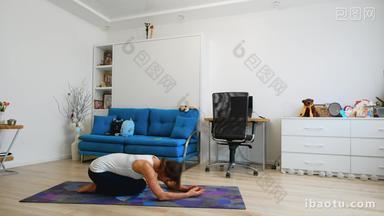 Young woman practicing yoga at home, stands in supported headstand